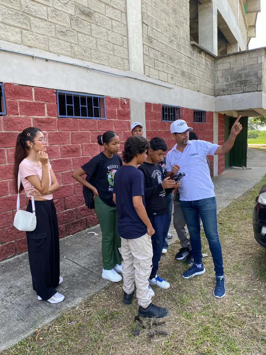 Docente explicando a estudiantes el manejo de un dron en una clase práctica al aire libre